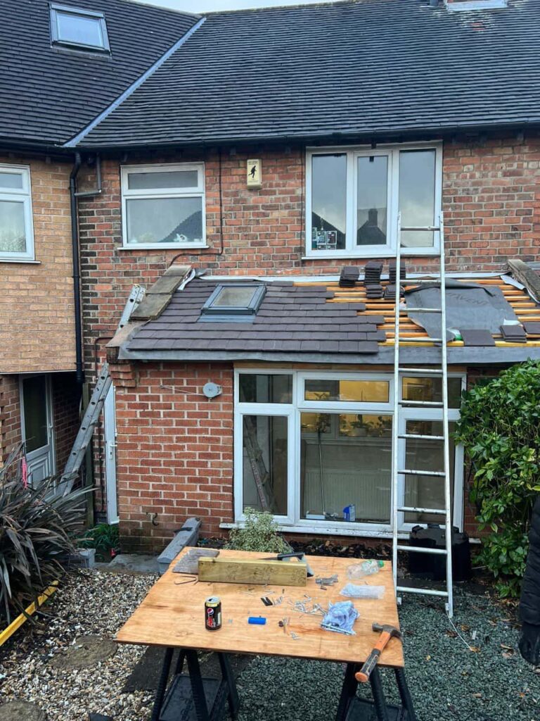 This is a photo of a roof extension that is having new roof tiles installed. This is a photo taken from the roof ridge looking down a tiled pitched roof on to a flat roof. Works carried out by Castle Donnington Roofing Repairs